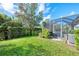 Landscaped backyard with spacious lawn and screened pool area at 9973 Holopaw St, Englewood, FL 34223