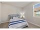 Cozy bedroom with a blue striped comforter and window at 11925 Bohemian Pl, Venice, FL 34293