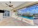 Enclosed pool with blue water, stone surround, waterfall feature, and ceiling fan at 1219 Nantucket Rd, Venice, FL 34293