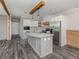 Modern kitchen boasts white cabinets, stainless steel appliances, marble countertops and backsplash and wood beam accents at 127 Nautical Dr, North Port, FL 34287