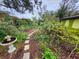 Landscaped backyard featuring a stone pathway, bird bath, and lush garden surroundings at 231 Victoria Rd, Venice, FL 34293