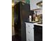 A kitchen featuring a modern black refrigerator adjacent to white cabinets and drawers, providing a contemporary look at 231 Victoria Rd, Venice, FL 34293