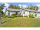 Condo exterior with gray roof, white garage door, and lush landscaping at 605 Apple Ln, Englewood, FL 34223