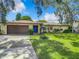 Single story home with brown garage door, blue front door, and well-manicured lawn at 2512 Regatta Dr, Sarasota, FL 34231