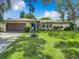 Single story home with brown garage door, blue front door, and lush green lawn at 2512 Regatta Dr, Sarasota, FL 34231