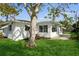 Side view of a charming white house with lush green lawn and mature tree at 352 Gardenia Rd, Venice, FL 34293