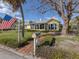 Charming yellow house with mature trees and American flag at 104 Sunrise Dr, Nokomis, FL 34275