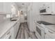 Contemporary kitchen with white cabinets, stainless steel sink, and grey wood flooring at 510 Harbor S Dr, Venice, FL 34285