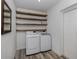 Laundry room with floating wood shelving, stainless steel appliances, and wood look flooring at 510 Harbor S Dr, Venice, FL 34285