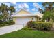 Inviting yellow house with a white garage door and lush landscaping at 714 Brightside Crescent Dr # 8, Venice, FL 34293