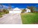 White house with three-car garage and green lawn at 8920 Bantry Bay Blvd, Englewood, FL 34224