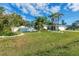 Landscaped front yard with lush grass, palm trees, and a white fence at 1030 Phorus Rd Rd, Venice, FL 34293