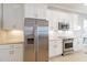 Kitchen area with stainless steel appliances, white cabinets, tile floors, and decorative tile backsplash at 10637 Corkwood Ct, Venice, FL 34293