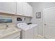 Bright laundry room equipped with a washing machine, dryer, sink, and ample storage space at 10637 Corkwood Ct, Venice, FL 34293