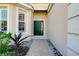 Front entry with green door, brick walkway, and landscaping at 11394 Dancing River Dr, Venice, FL 34292