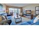 Bright living room with comfy blue sofas, a large TV, and access to a screened patio at 1174 Bird Bay Way # 107, Venice, FL 34285
