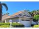 Exterior elevation of a single-story home with a tiled roof, white garage door, and lush landscaping at 1206 Berkshire Cir, Venice, FL 34292