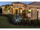Elegant stucco home with manicured landscaping, paver driveway, and inviting entryway enhanced by soft lighting at 169 N Cayman Isles Blvd, Englewood, FL 34223