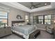 Spacious main bedroom features a tray ceiling, ceiling fan, and three large windows overlooking the yard at 169 N Cayman Isles Blvd, Englewood, FL 34223