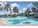 Community pool features a zero entry, blue umbrellas, numerous chairs, and a pool house in a tropical setting at 169 N Cayman Isles Blvd, Englewood, FL 34223