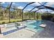 An angled view of a screened pool and jacuzzi with tiled edges, bright sunshine and verdant landscaping at 169 N Cayman Isles Blvd, Englewood, FL 34223