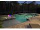 Nighttime view of a screened-in pool and spa illuminated by colorful lights and landscape lighting at 169 N Cayman Isles Blvd, Englewood, FL 34223