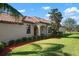 Tan house with brown tile roof, landscaping, and a view of the backyard at 20049 Benissimo Dr, Venice, FL 34293