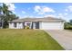 One-story home with a white exterior, attached garage, and well-maintained lawn at 4467 Cinderella Cir, North Port, FL 34286
