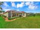 Large backyard with screened patio, lush lawn, and golf course view at 5633 Whispering Oaks Dr, North Port, FL 34287