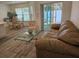 Comfortable living room featuring a plush sofa, glass coffee table, and sliding glass doors to the patio at 606 Marcus St # 26, Venice, FL 34285