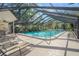Community pool with screened enclosure, lounge chairs, and surrounding lush landscape at 6906 Woodwind Dr # 12, Sarasota, FL 34231
