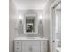 Bathroom vanity with white cabinetry, quartz countertop, sconce lighting, and a large mirror at 842 Nokomis S Ave, Venice, FL 34285