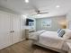 Bright bedroom featuring light walls, wood-look flooring, ceiling fan and a TV above a white, cottage style dresser at 842 Nokomis S Ave, Venice, FL 34285