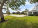 Spacious front yard featuring lush green grass, mature trees, and a beautifully paved driveway at 842 Nokomis S Ave, Venice, FL 34285