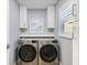 Convenient laundry room with front-loading washer and dryer, upper cabinets, and a bright window at 842 Nokomis S Ave, Venice, FL 34285