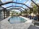 A screened-in pool area with a dark frame around the enclosure and two dark-blue lounge chairs at the far end at 842 Nokomis S Ave, Venice, FL 34285