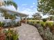 Paver walkway leading to blue home, surrounded by lush greenery and landscape at 842 Nokomis S Ave, Venice, FL 34285