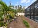 Landscaped backyard with mulch, rocks, short green plants, and palm trees next to a fenced pool enclosure at 842 Nokomis S Ave, Venice, FL 34285