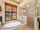 Bathroom featuring an oval tub, walk-in shower, and large window at 995 Chickadee Dr, Venice, FL 34285