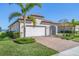 Single-Gathering home exterior showcasing a white garage door and tropical landscaping at 24176 Spartina Dr, Venice, FL 34293