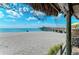 Beachfront view with pier, under a thatched roof at 6255 Aventura Dr, Sarasota, FL 34241