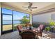Screened patio featuring a ceiling fan, wicker furniture, and a tranquil lake view at 660 Ravello Blvd, Nokomis, FL 34275