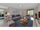 Bright living room with gray sofa set and coffee table over a navy rug, complemented by large windows at 10185 Colubrina Dr, Venice, FL 34293