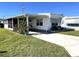 White mobile home with carport, golf cart, and green lawn at 218 Trailorama Dr, North Port, FL 34287