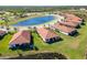 Aerial view of homes with red tile roofs and a pond at 23924 Skyflower Ct, Venice, FL 34293