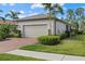 Tan two-car garage with brick pavers and lush landscaping at 2539 Brassica Dr, North Port, FL 34289