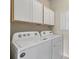 Laundry room with Whirlpool washer and dryer and overhead cabinets at 2539 Brassica Dr, North Port, FL 34289
