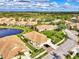 Aerial view of a luxury community with houses, lush landscaping, and a lake at 4980 Whispering Oaks Dr, North Port, FL 34287