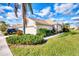 Tan house exterior with lush landscaping, a two-car garage, and a walkway at 4980 Whispering Oaks Dr, North Port, FL 34287
