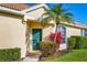Inviting front entrance with a teal door and colorful landscaping, enhancing curb appeal at 4980 Whispering Oaks Dr, North Port, FL 34287